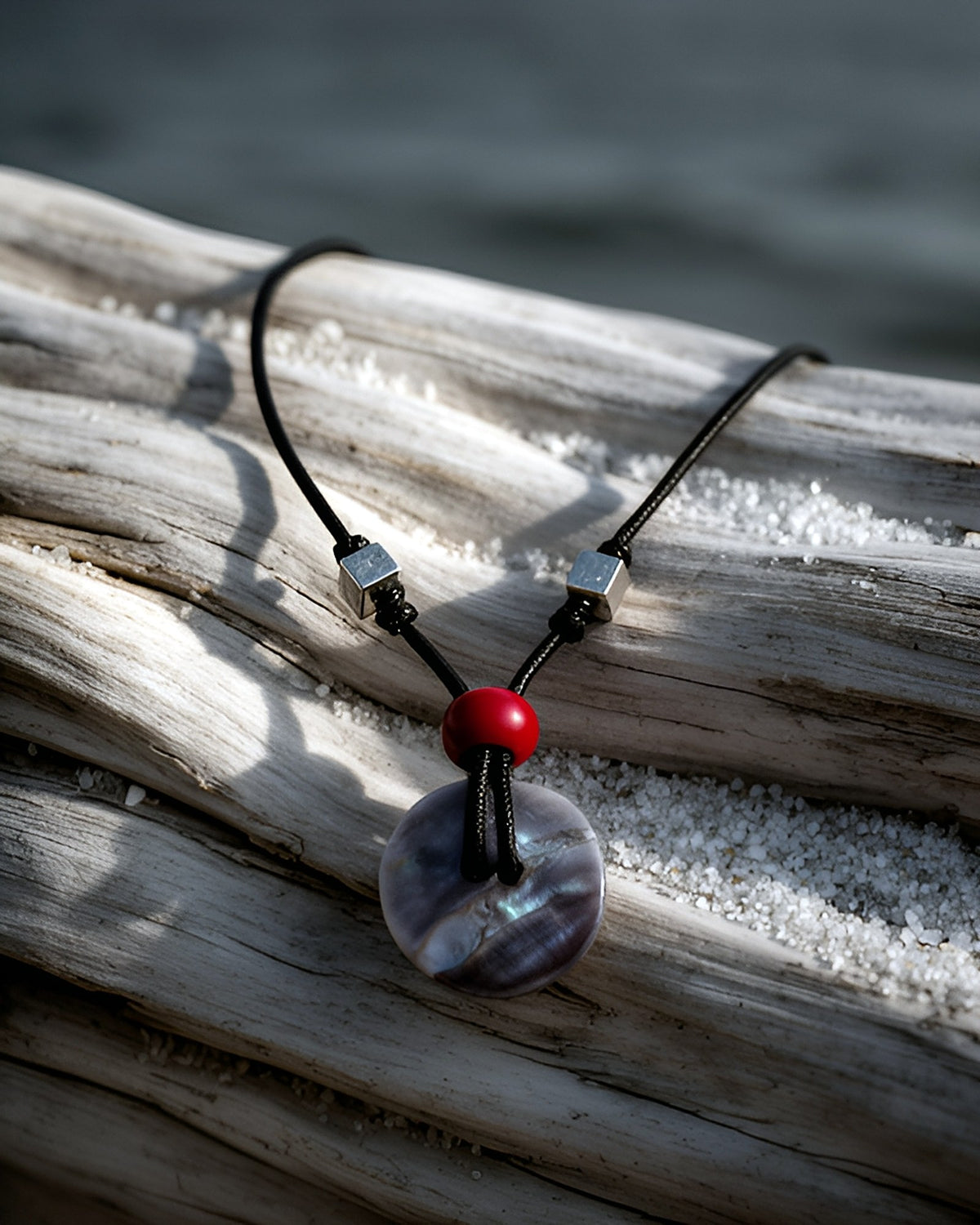 NK-06 abalone disc pendant — on driftwood